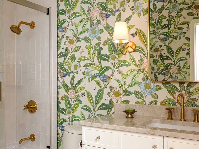 Lake Oswego hall bath remodel with green botanical bird wallpaper, white vanity, and unlacquered brass fixtures
