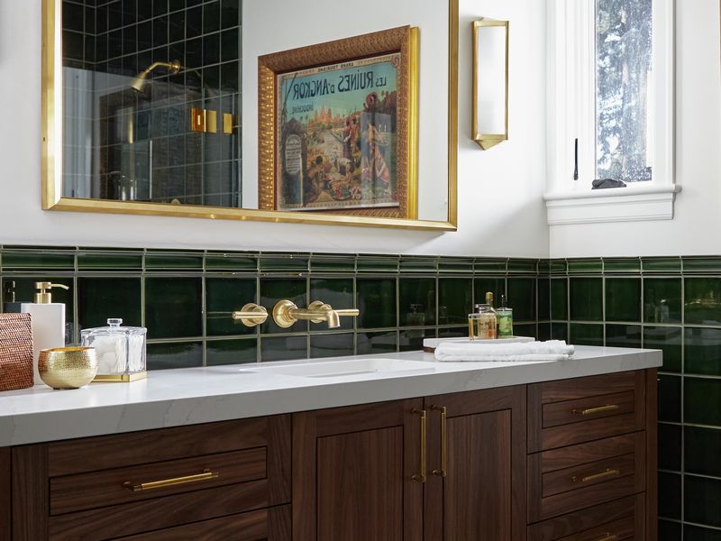 Vancouver bath remodel with emerald green tile wainscot, walnut vanity, brass wall-mount faucet, and gold-framed mirror