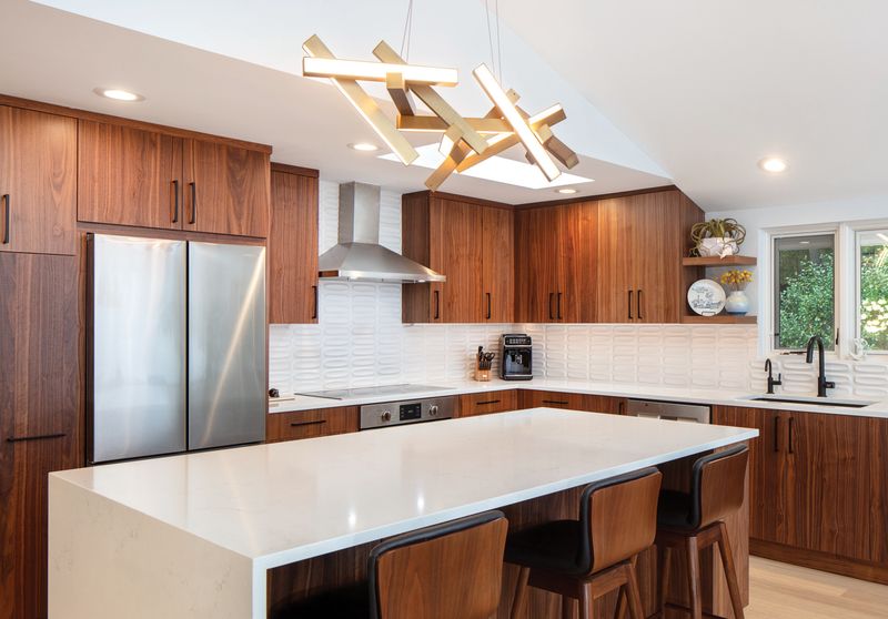 Midcentury Bellevue kitchen remodel with walnut cabinets, sculptural brass chandelier, quartz island, and skylight