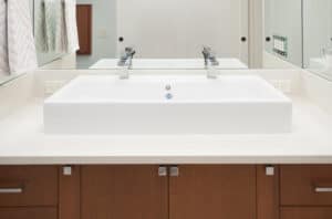 White, double faucet vanity with mahogany drawers.