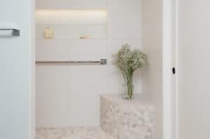 White, subway tile, walk-in shower with chrome grab bars and a built in shower seat.