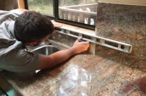 Man checking the plane of a window sill with a spirit level tool.