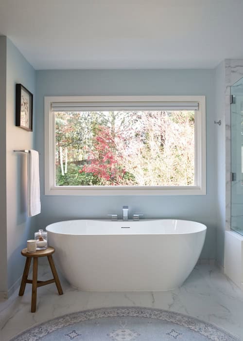 Signature Hardware oval acrylic freestanding tub below a window.