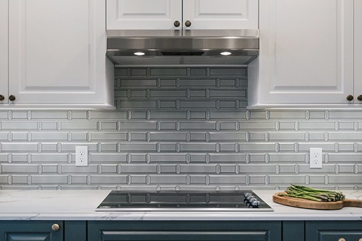 Glass cooktop with vent built into cabinets with gray backsplash