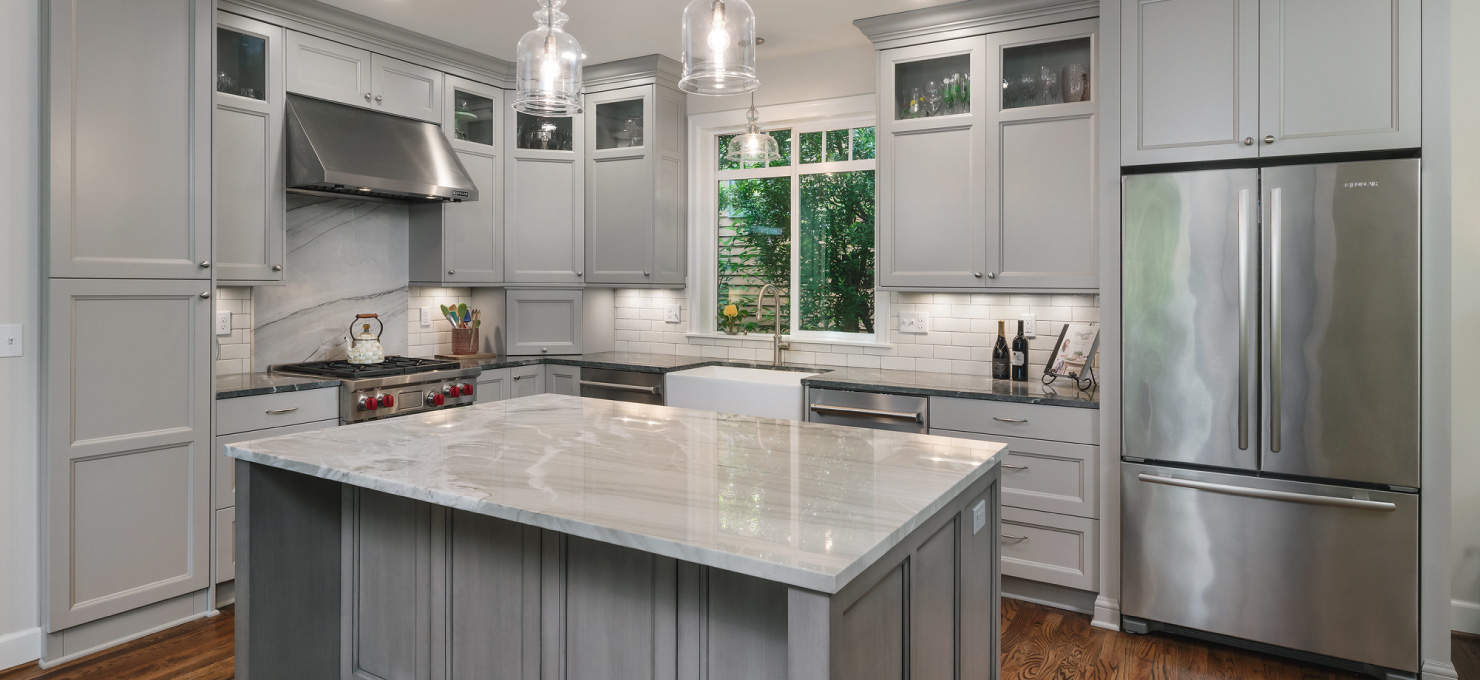 Kitchen with a center island, stainless steel appliances, and grey paneled cabinets.