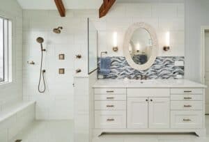 Titled shower alcove with a glass partition next to a white quarts top vanity.