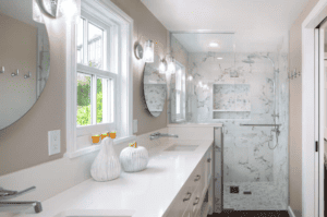 Bathroom with a double vanity along the wall, white countertops, round wall mirrors above the sinks, and a glass box shower.