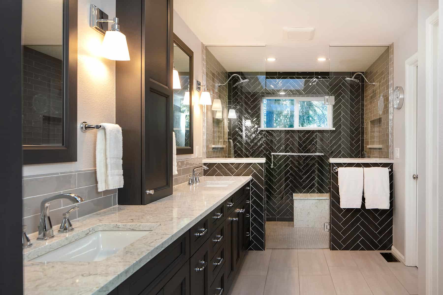 Large primary bathroom with black cabinets and shower tile.