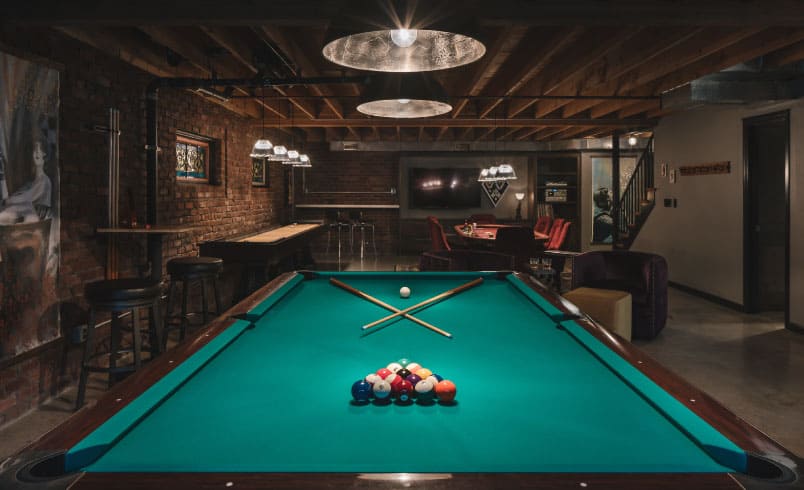 Basement man cave with pool table and exposed brick wall