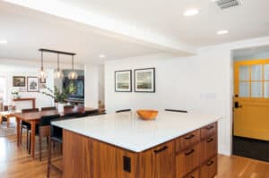 Large kitchen island with a white countertop and oak wooden cabinets with black pull handles.