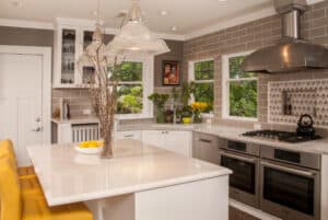 Kitchen with central island with three yellow bar chairs.