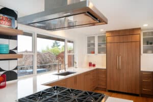 Six-burner stove beneath a stainless steel ceiling vent.