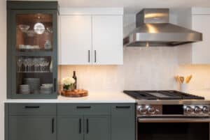 Kitchen with grey cabinetry with matte black pull handles.