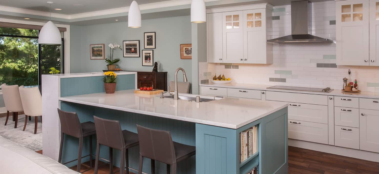 Contemporary kitchen with white cabinets, a center island with quartz countertop, blue wood paneling and three bar stools.
