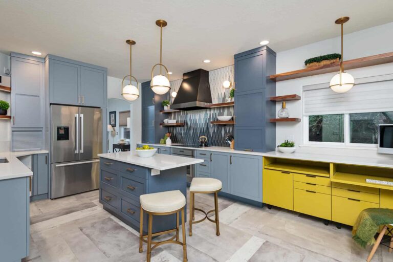 Modern kitchen with blue wooden cabinets, a center island, white countertops, and stainless steel appliances.