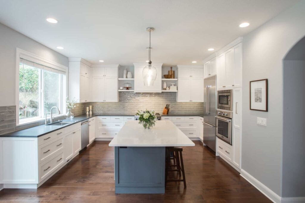 U shaped kitchen with white cabinets and dark countertops, white cabinets, stainless steel appliances.