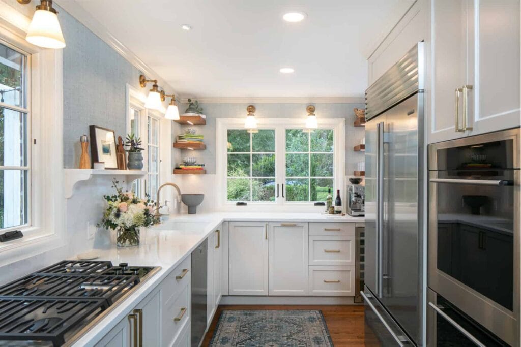 U shaped kitchen with white countertops, white cabinets, stainless steel appliances, and a gas range.