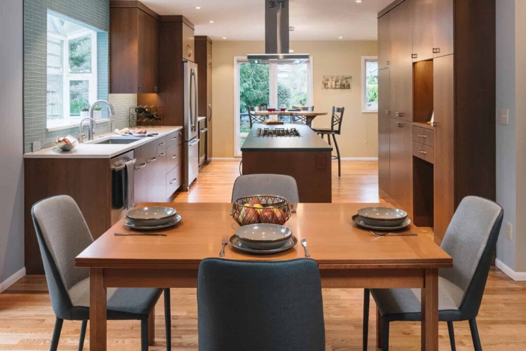 Wooden dining room table with four seating arrangements next to a living room space.