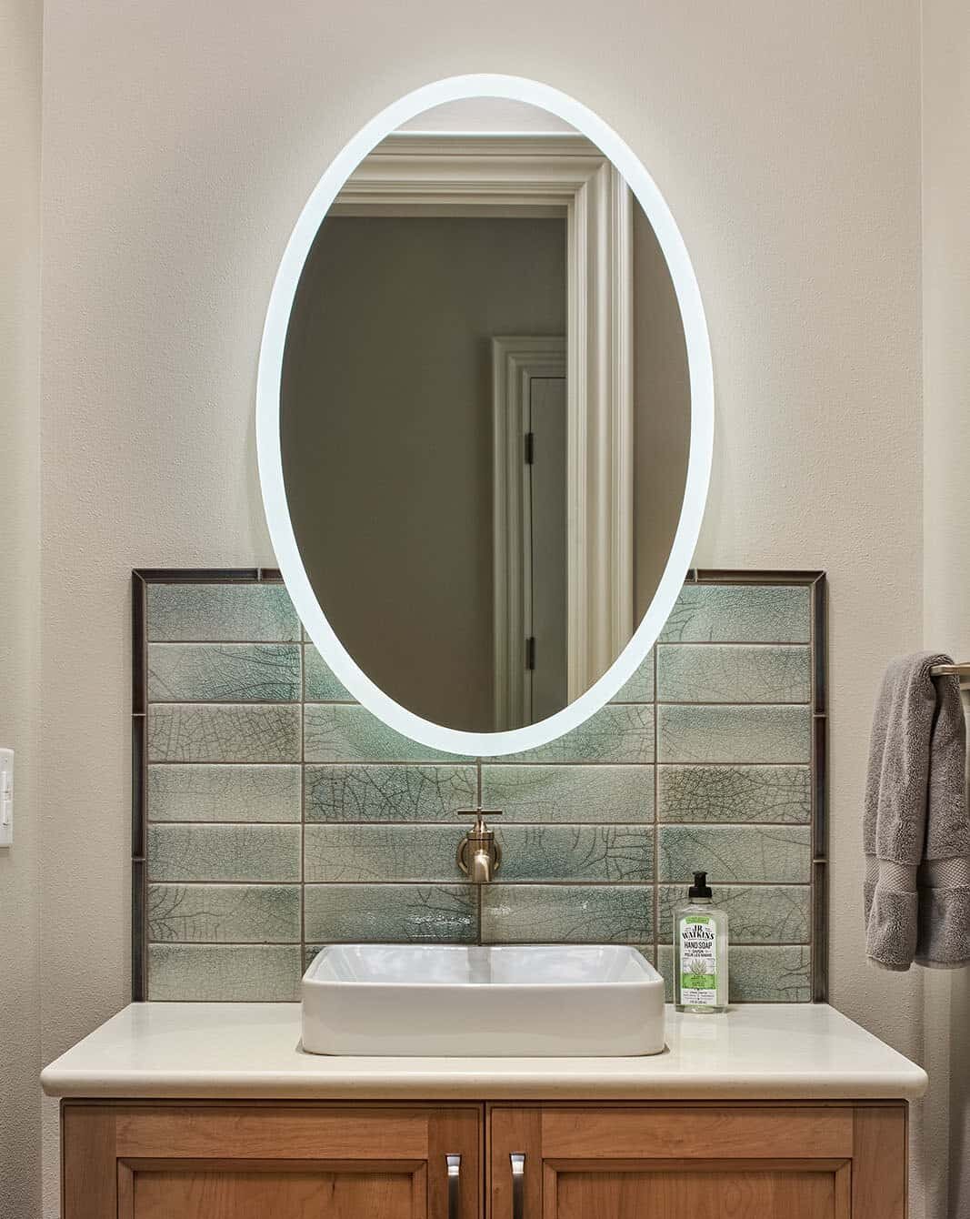 Powder bath single sink vanity with oval lighted mirror.