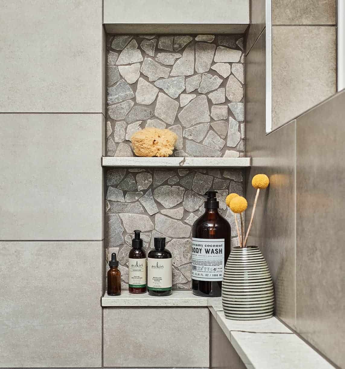 A stone tile shower niche bottom shelf that extends as a ledge around a shower perimeter.