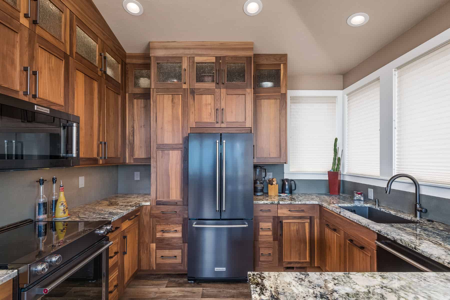 Kitchen with granite countertops, walnut cabinets with a unique modern door style, refrigerator, and electric stovetop.