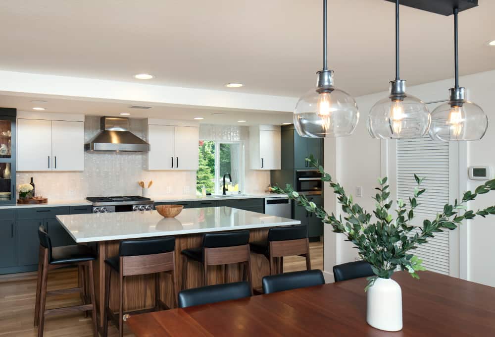 Kitchen remodeling project with green cabinets and a large center island with four wooden stools around the countertop.