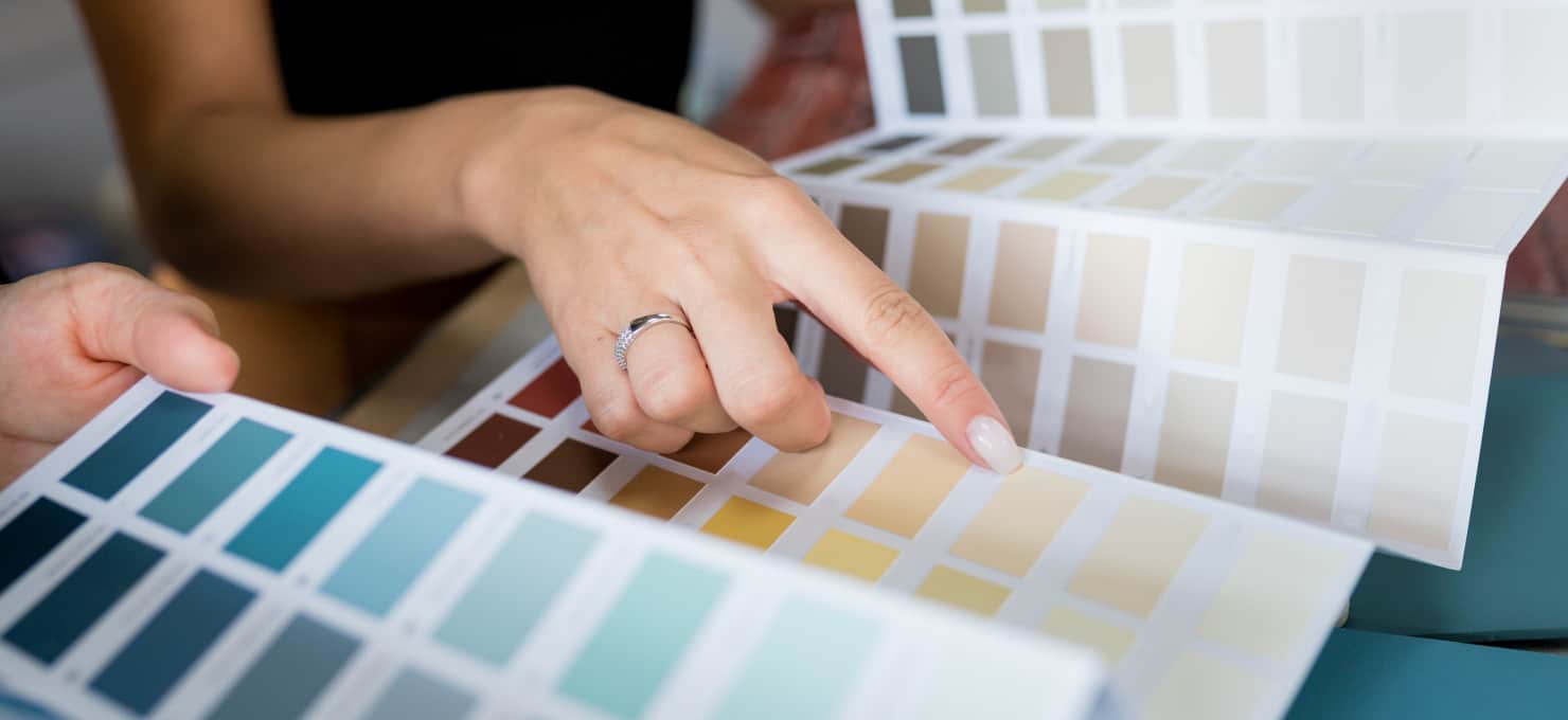 Person pointing to yellow paint samples in a paint sample booklet.