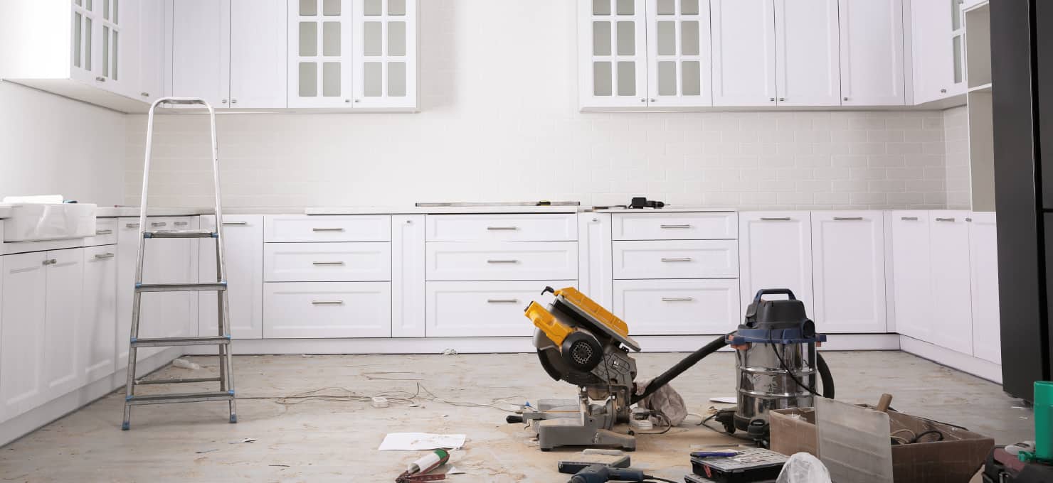 Power saw and vacuum on the floor of a kitchen being remodeled.