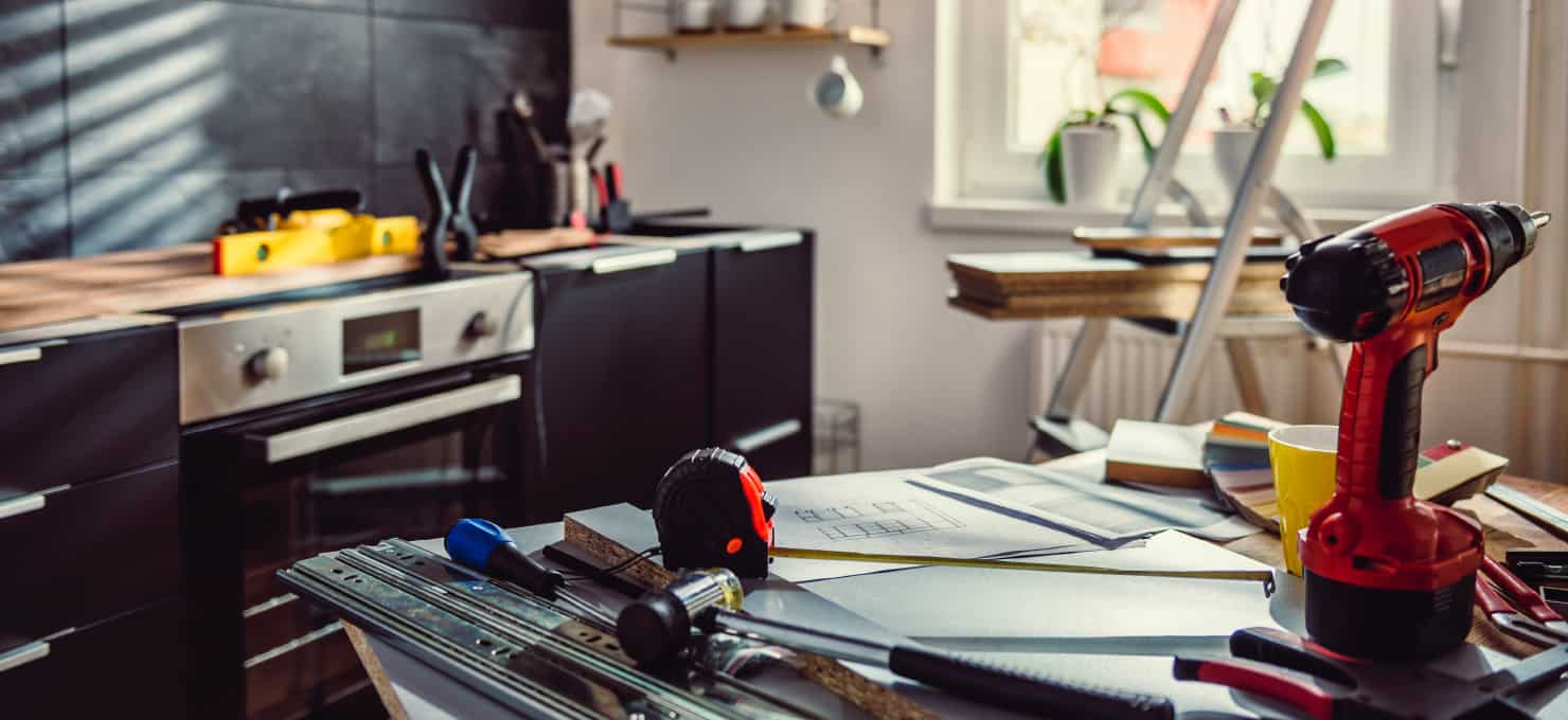 Renovation tools and papers on top of a table in a kitchen.
