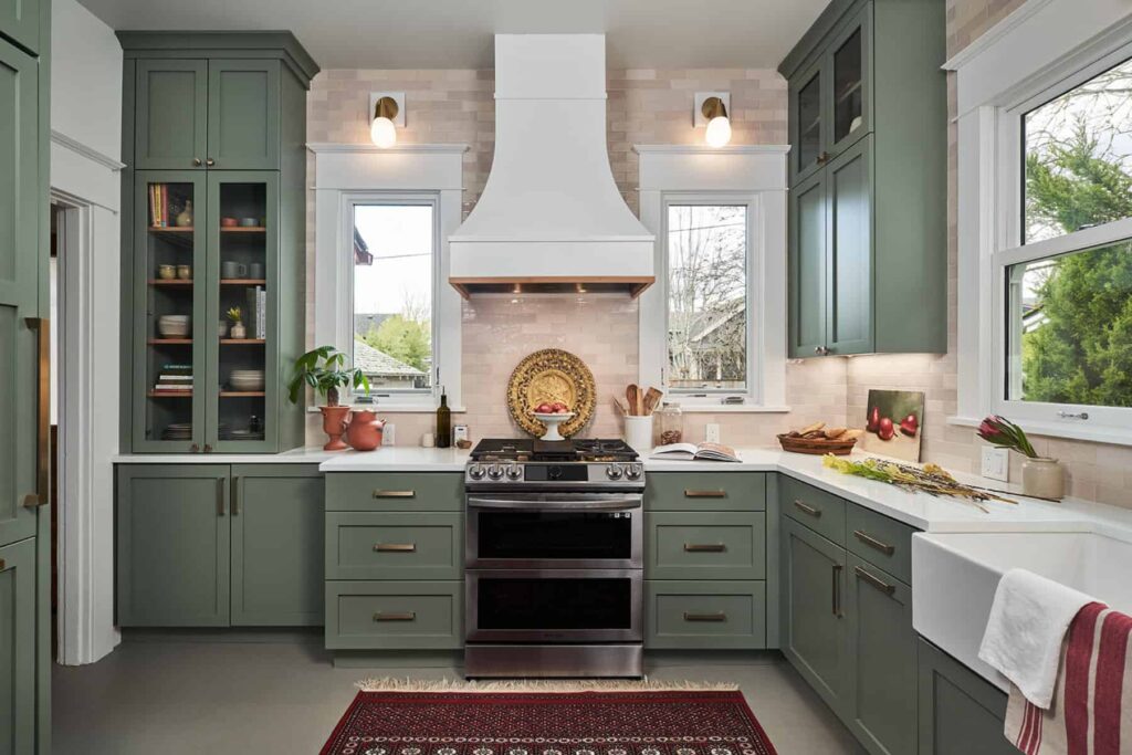 Kitchen with green shaker cabinetry, white marbled countertops, and a double over and range.