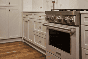 Kitchen with a stainless steel range, light grey panel cabinetry, and oak hardwood floors.