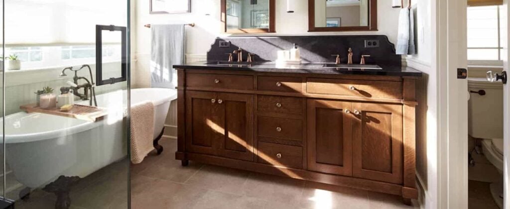 Primary bathroom with a dark wood custom double vanity next to a clawfoot tub.