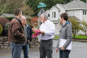 Two home remodeling consultants talking to two homeowners outside.