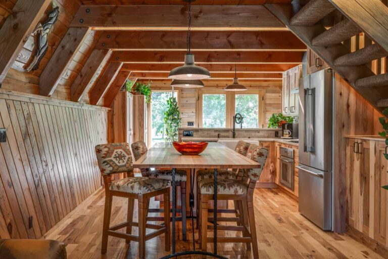 Four-seater high table with four wooden upholstery high-chairs in a cozy cabin home kitchen.