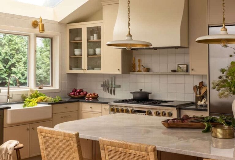 Sunlit kitchen with a large island, skylights, white cabinetry, stainless appliances, and high chairs along the island.
