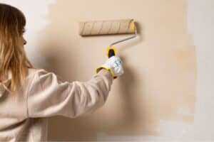 A woman using a roller to paint a wall.