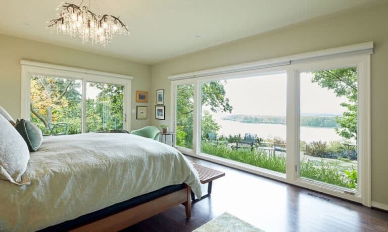 Bedroom with large windows and a view of the trees outside.)