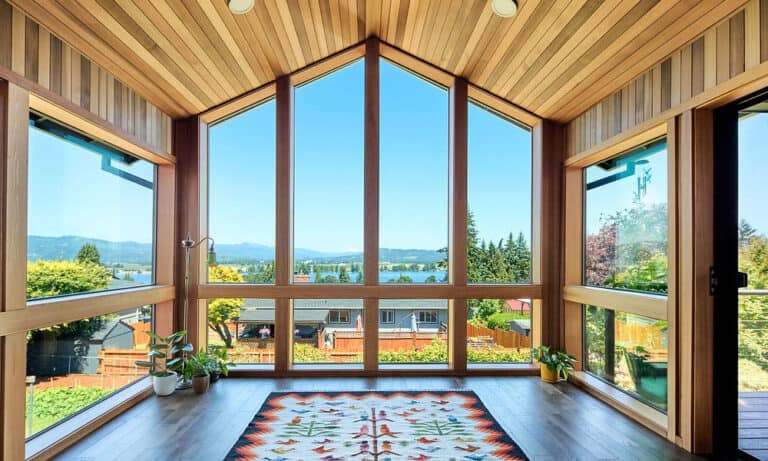 Bright sunlit great room with expansive glass walls and a view of the outdoors.)