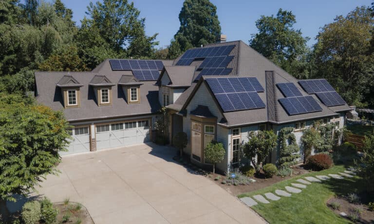 Modern home with multiple solar panels and a spacious two-car garage.)