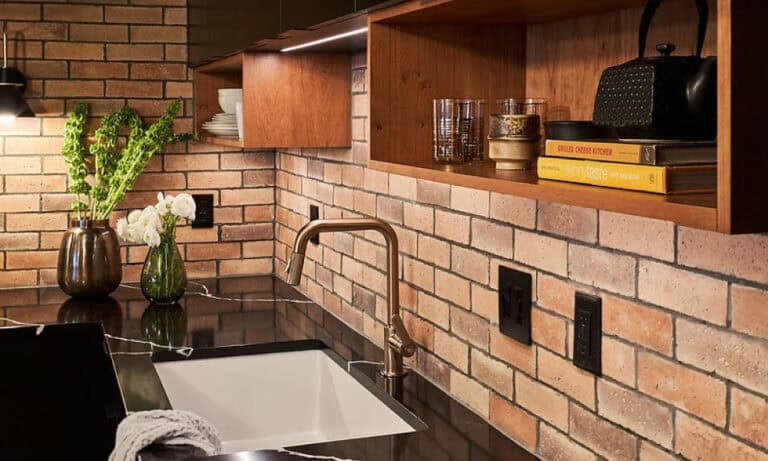 Sleek kitchen with a subway brick backsplash, dark countertops, and open wooden shelving.)