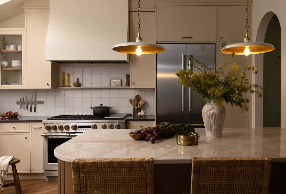 Sunlit kitchen with a large island, skylight, white cabinets, stainless appliances, and high chairs along the edge.