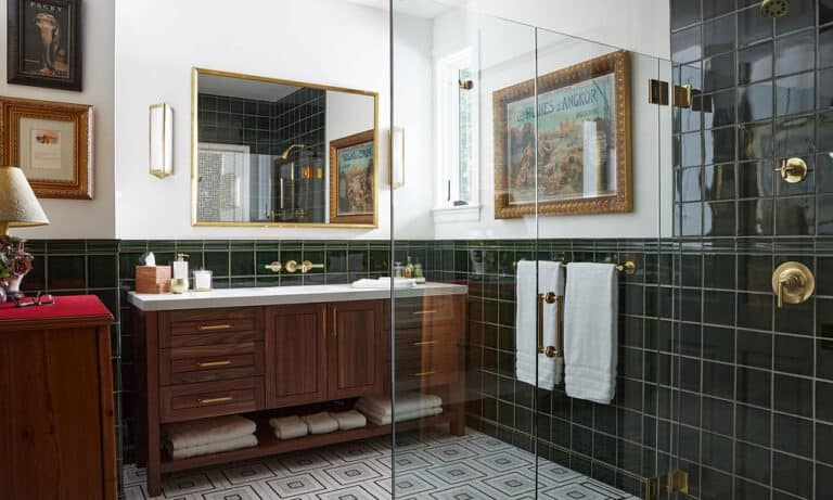 Primary bathroom with a walk in shower, green tile, and a double sink vanity.)