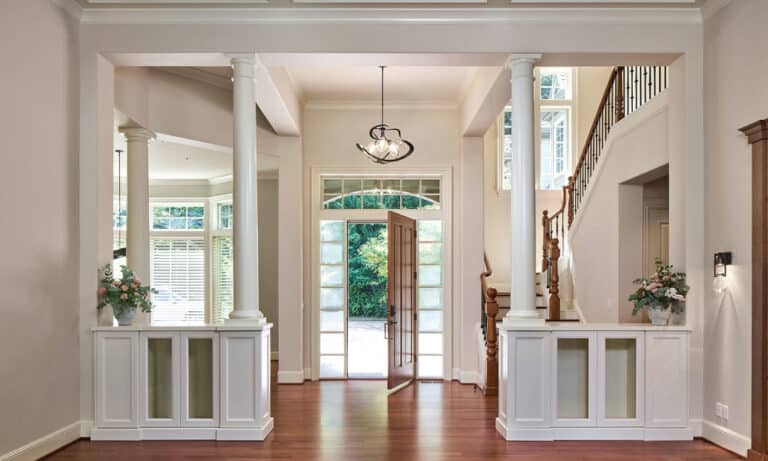 Bright entry hall with white columns, hardwood floors, and a view to a front yard.)