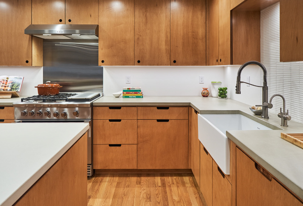 Kitchen with plywood cabinets and drawers with maple veneer, a kitchen island, and concrete countertops.