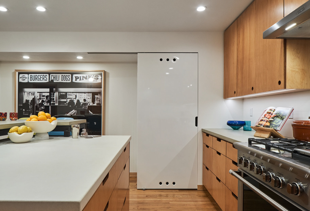 Kitchen with plywood cabinets and drawers with maple veneer, a kitchen island, and concrete countertops.