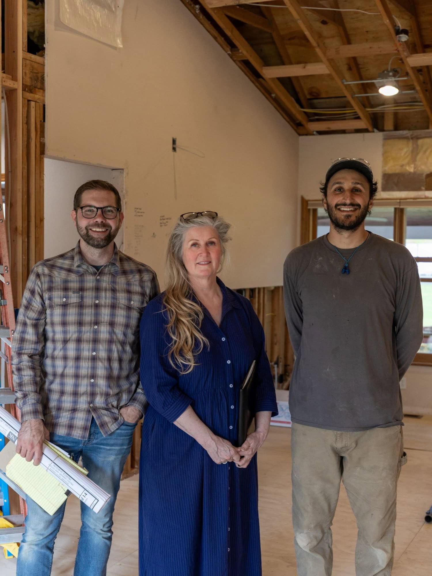 A designer, project manager, and carpenter standing in a home under construction