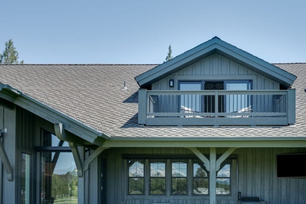 A Central Oregon home exterior with a new roof and a large dormer with a balcony and sliding glass door