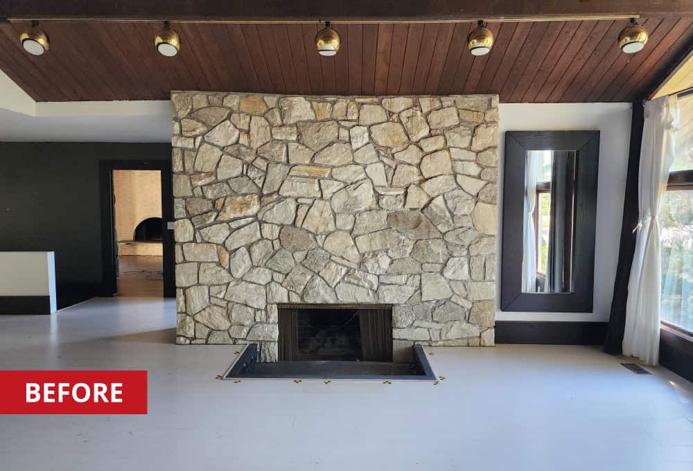 Stone fireplace in open-concept living room with cathedral ceiling.