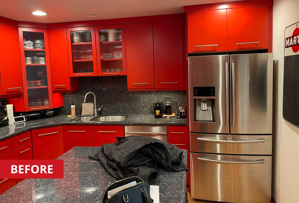 Kitchen cabinets with red cabinet faces around a stainless steel refrigerator.