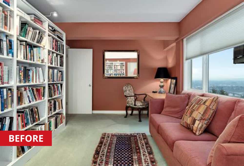 A red couch opposite a white bookshelf in a home den.